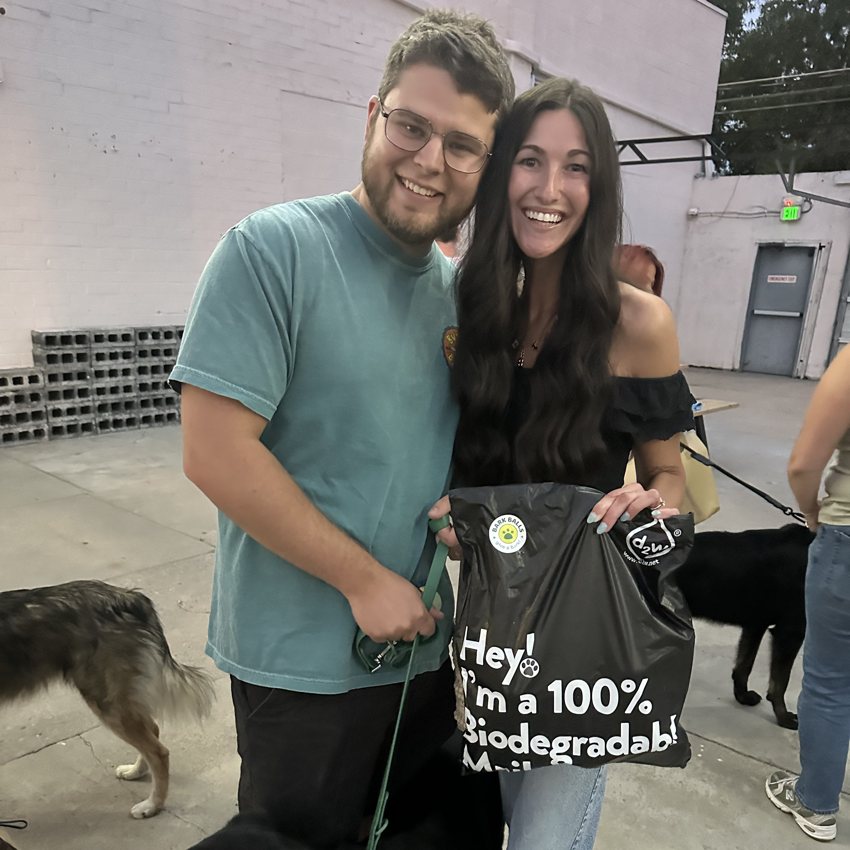 A couple who won a Bark Balls giveaway at a Denver Dog Mom event, holding their biodegradable mailer